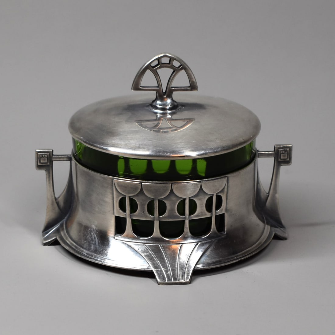 A WMF Art Nouveau box and cover with green glass inset: A German Art Nouveau box and cover with original green glass insert by WMF circa 1900. Stamped WMF, Ostrich mark amd embossed model 345. Silver plated britania metal, with geometric open designwork. A