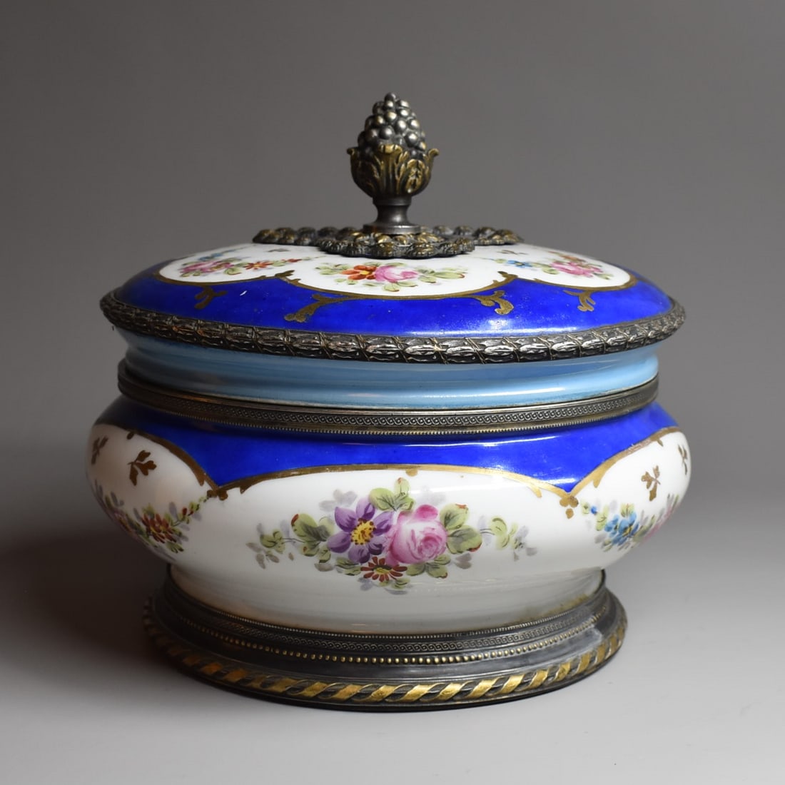 A large SEVRES / Sevres style bronze mounted porcelain bombonniere/ candy dish: A large antique or vintage Sevres / Sevres style bronze mounted porcelain bombonniere / canded dish / circular box and cover. The porcelain hand painted with garlands of flowers in cartouches within a