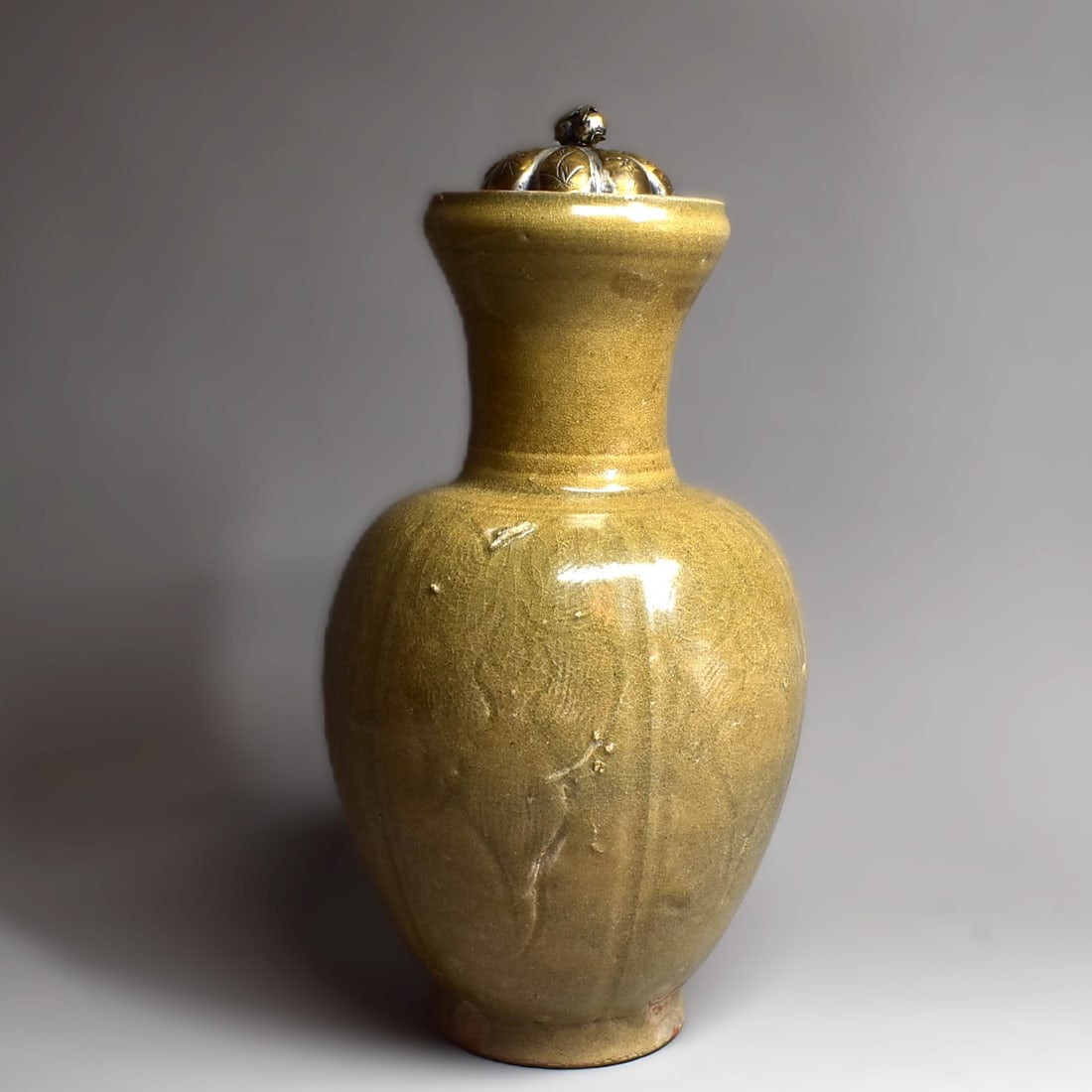 A Chinese 'Longquan' celadon-glazed incised vase: A Chinese 'Longquan' celadon-glazed and incised vase, the rounded sides rising from a slightly tapered foot,, the neck with everted rim. The exterior carved with floral motifs, covered overall in an o