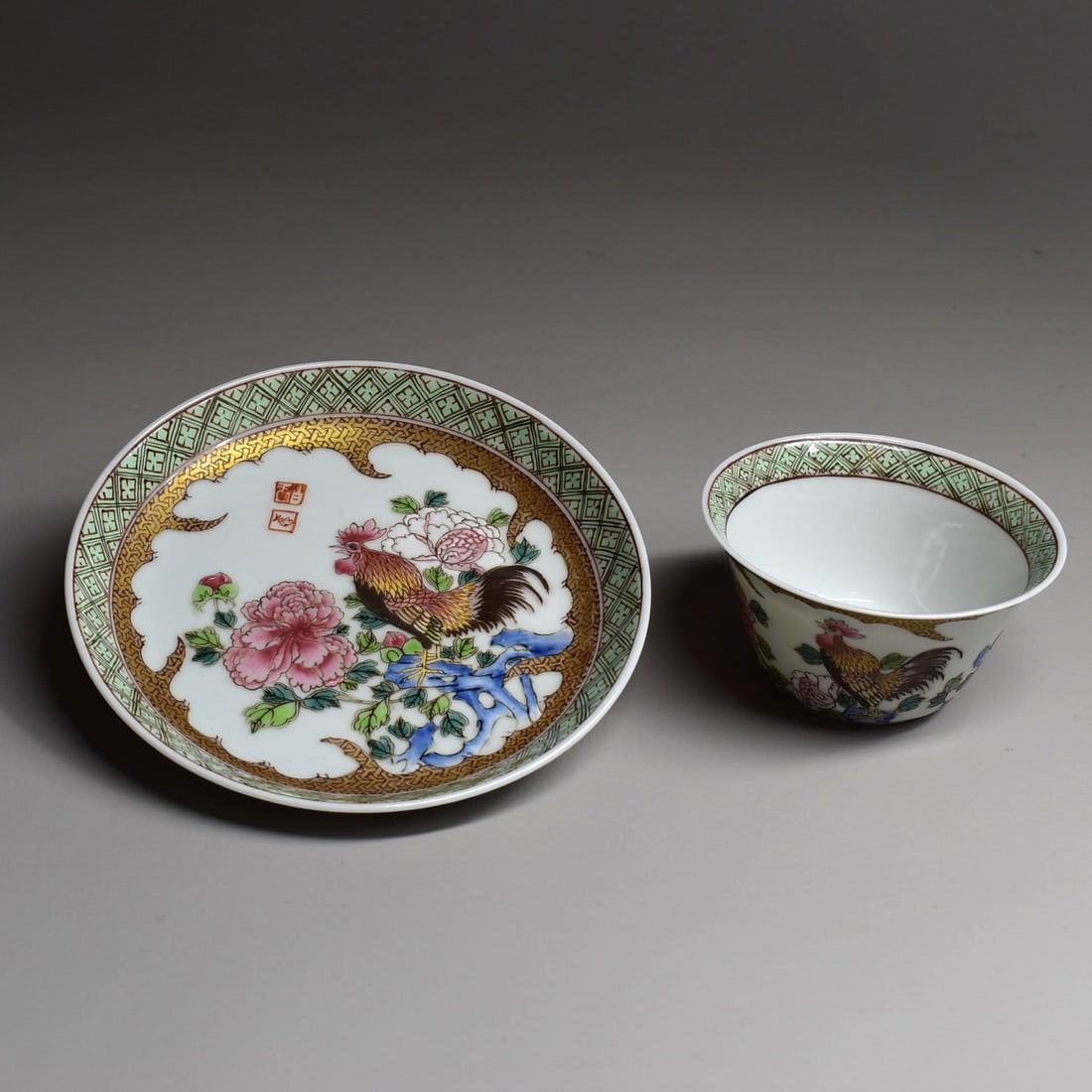 A signed Chinese famille rose porcelain tea bowl and saucer with rooster: A delicate Chinese famille rose porcelain tea bowl and saucer, each piece finely enamel decorated in bright enamels with a rooster, with yellow and orange wings and a black tail. Each piece with a two