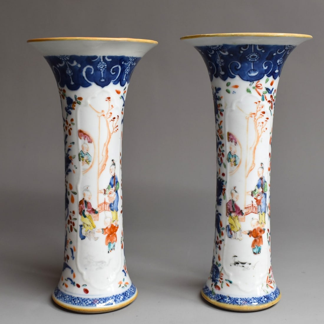A pair of Antique Chinese export porcelain trumpet vases: A small pair of fine Chinese export porcelain trumpet vases with enamel decorated palatial scenes on a blue and white background. Late 18th/ early 19th century. Approximate measurements: 7 1/4"H x 3 1