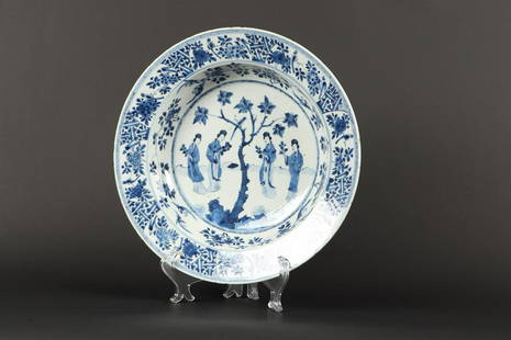 A porcelain dish decorated with four Guan-Yin's near a tree: A porcelain dish decorated with four Guan-Yin's near a tree in the center and floral decoration in divisions on the edge, marked in the period. China, Kangxi.Diam. 34 cm.