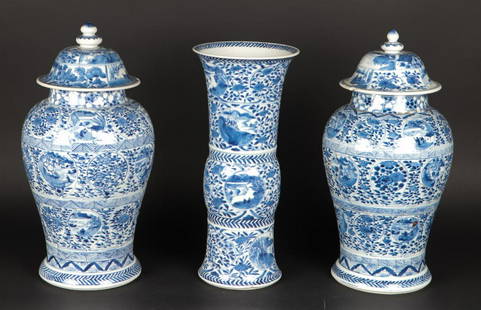 A porcelain garniture set consisting of two lidded vases an: A porcelain garniture set consisting of two lidded vases and a beaker vase, decorated with floral decor. China, Kangxi.H.: (bekervaas) 32,5 cm.