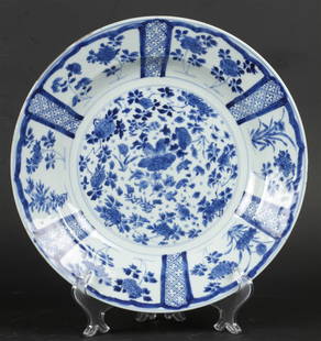 A porcelain dish, with bordered outer rim and rich floral d: A porcelain dish, with bordered outer rim and rich floral decoration. China, Kangxi.Diam.: 32 cm.