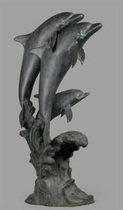 A bronze ageing statue of jumping dolphins.