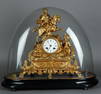 A gold-painted zamac mantel clock decorated with a knight on horseback, in a glass dome.