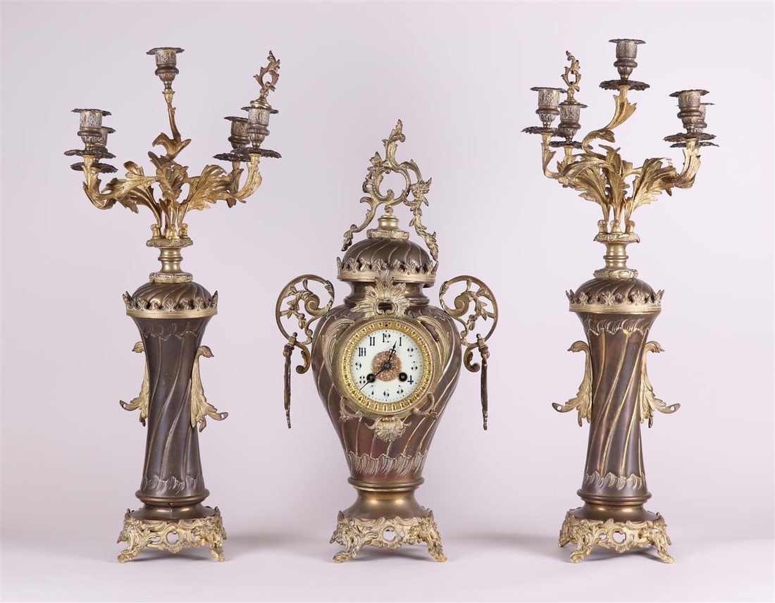 A French Garniture de ChÃ©minÃ© or clock set, consisting of a mantel clock and two five-armed: A French Garniture de ChÃ©minÃ© or clock set, consisting of a mantel clock and two five-armed candlesticks.H.: 71 cm.