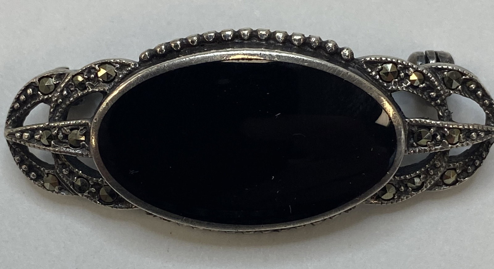ANTIQUE STERLING SILVER MARCASITE BROOCH BLACK STONE: ANTIQUE STERLING SILVER MARCASITE BROOCH BLACK STONE The brooch is pre-owned Weight: 7.6 g Size: 1 1/2 x 5/8 in SHIPPING FEE CANADA 10.00$ USA 15.00$ Combined shipping is available for an extra fee, b