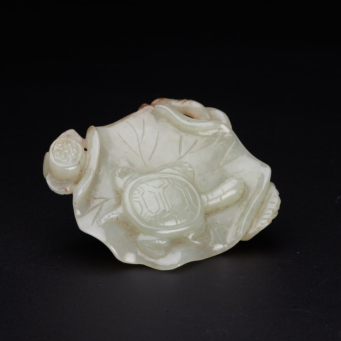 A pale celadon jade plaque 'turtle and lotus', Qing Dynasty: A pale celadon jade plaque 'turtle and lotus', Qing Dynasty intricately carved in relief with a turtle resting on a lotus leaf, the turtle's shell pattern and veins of the leaf finely detailed, on the