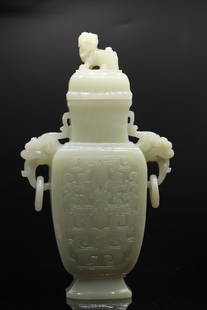 A Chinese pale celadon jade archaistic vase and cover, Qing Dynasty / Republic period (Woolley &: A Chinese pale celadon jade archaistic vase and cover, Qing Dynasty / Republic period (Woolley & Wallis) the body carved in relief with stylised taotie and with animal mask and loose ring handles,