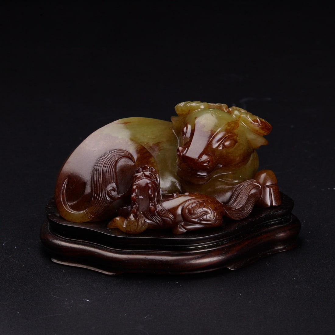 A yellow and russet jade carving 'ox and qilin', 18th century (Stockspring Antiques London, the: A yellow and russet jade carving 'ox and qilin', 18th century (member of The British Antique dealer's Association, the label) carved in the round, the ox in recumbent with four legs bent underneath it
