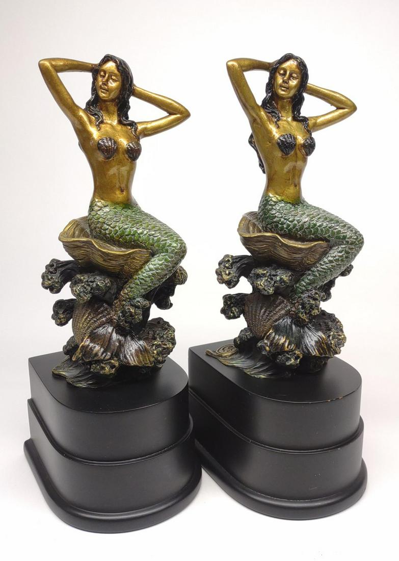 Pair of Brass Mermaid Bookends: Pair of imperial finish brass bookends with seated mermaid sculptures. Each is mounted on wooden black base. Back is mermaid figure is marked with SPI Gallery "S" mark. 10.5" tall.