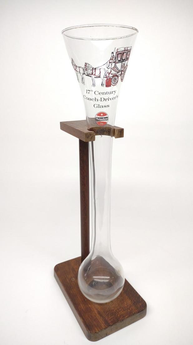 Heineken 1/2 Yard 17th C Coach Drivers Glass: Heineken 1/2 yard beer glass with wooden stand. Labeled 17th century Coach-Drivers Glass. Gold is worn on top rim. No chips or cracks.