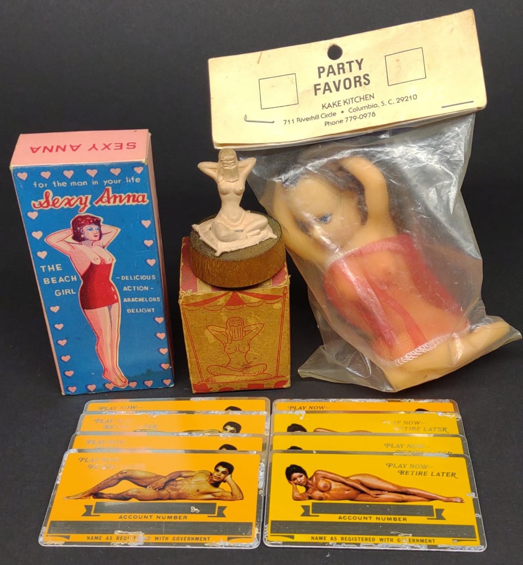 Vintage Nude Risque / Naughty Novelty Items: A group of vintage nude and risque items. Includes Party Favors nude female cake topper in unopened pack, novelty Fatima "The Harem Dancing Girl" figure with box, 8 metal 1970s risque ID cards, changi