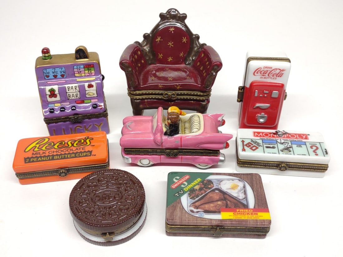 8 Figural Porcelain Pill Boxes: A group of 8 figural porcelain pill boxes. Many are marked "Midwest of Cannon Falls". Includes Reeses pill box with miniature candies, monopoly pill box with miniature car, Swanson TV dinner with mini