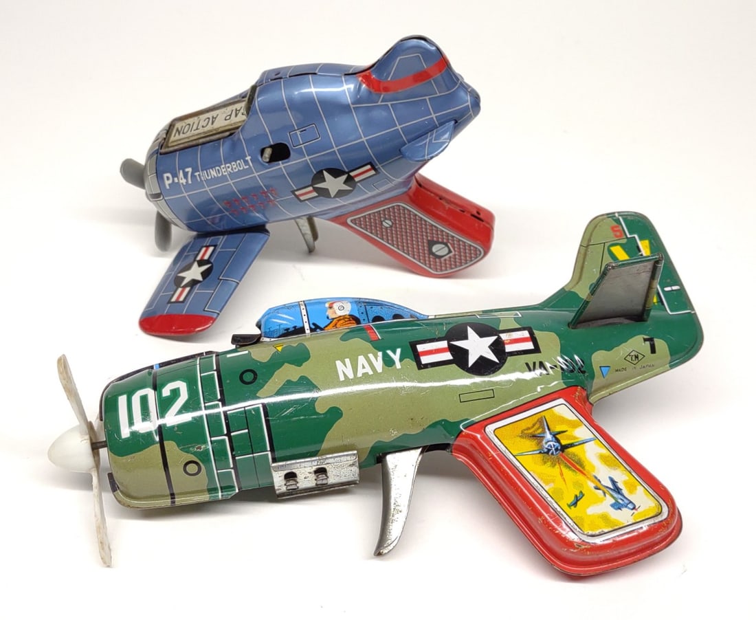 2 Japan Friction Trigger & Cap Fighter Plane Toys: Two vintage, 1950s, Japan tin litho plane toys. Includes T.N. friction powered trigger plane toy and friction P-47 THUNDERBOLT Cap Gun Firing Fighter Plane. Both are in good, working condition.