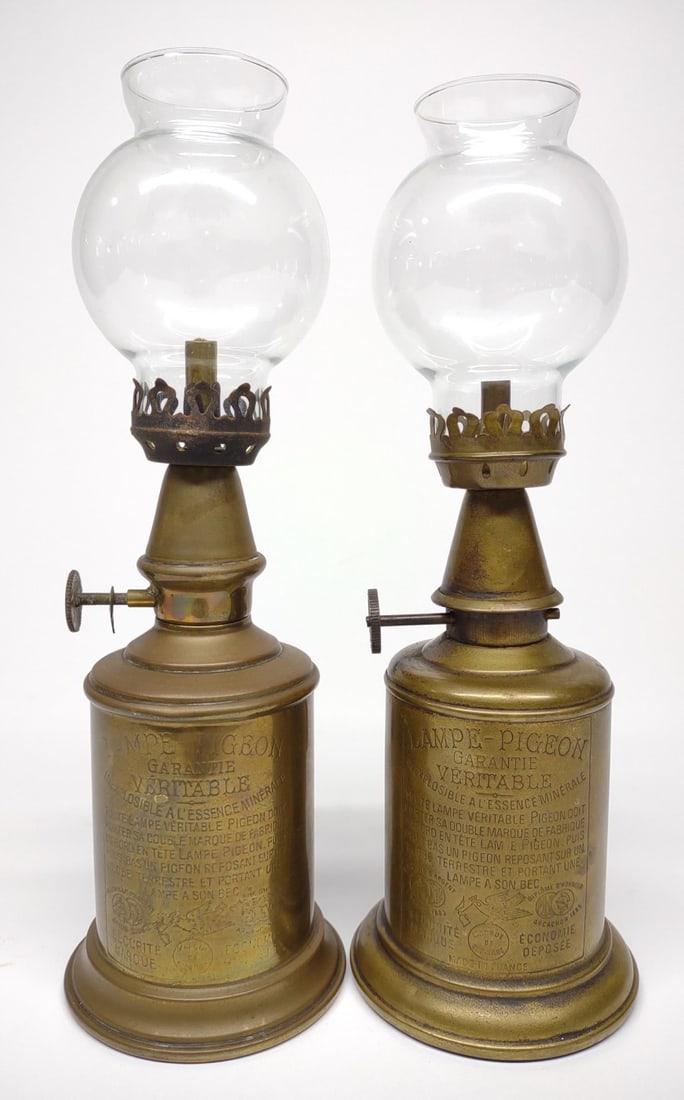 2 19th C. French Brass Pigeon Lamps: Pair of antique, 19th century, brass pigeon oil lamps. Both lamps include glass chimneys. Marked: Lampe Pigeon, Made in France. Measures 9 1/2" Tall.