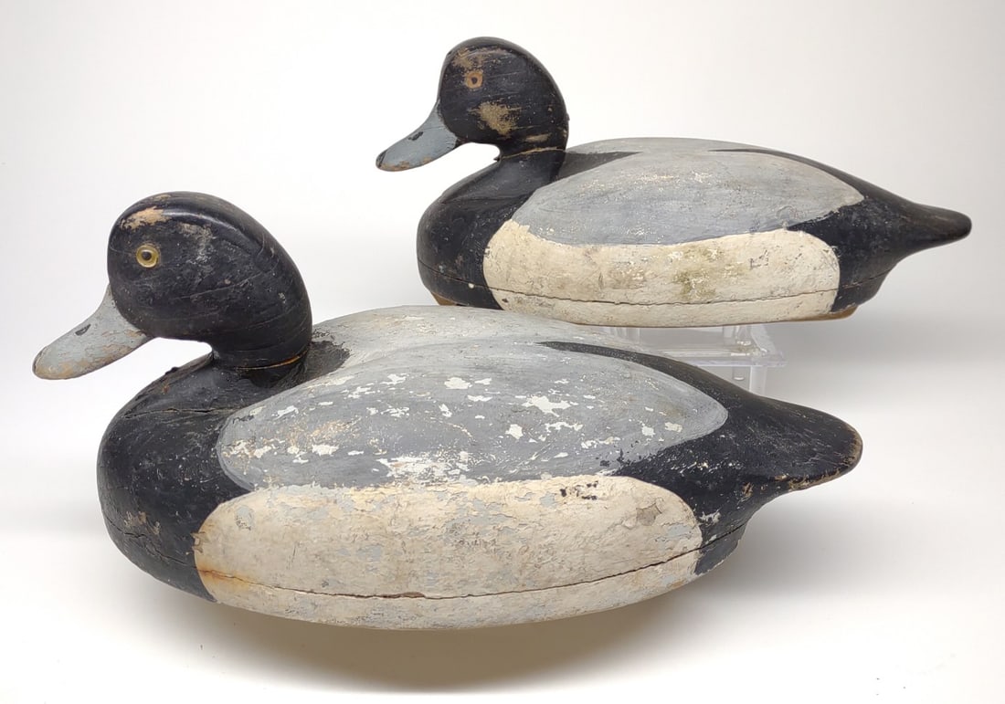 Pr of Wildfowler Bluebill Duck Decoys: 2 Wildfowler Decoy Co bluebill duck decoys. One with glass eyes, one with painted eyes. Undersides of both are stamped with circular Wildfowler Decoy Co marking. Chip on base of ones neck, the other h