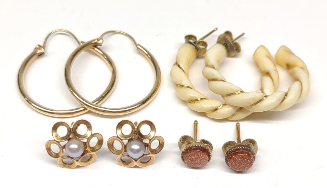4 Pairs of 14K Yellow Gold Earrings: 4 pairs of 14 karat gold earrings. Includes pair of hoop, sandstone studs (backings not gold), floral pearl studs, & bone carved spiral earrings. All tested for gold purity. Total weight: 4.29 grams.