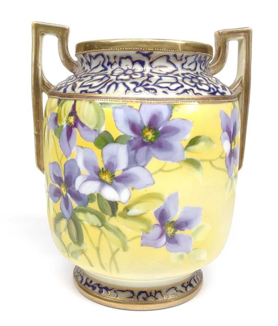 Nippon Floral Violets & Gold Enamel Vase: Antique, circa late 19th/early 20th century, hand painted porcelain Japan Nippon double handled vase. Featuring Purple violet flowers with purple and gold enamel trim accents and gold painted handles.