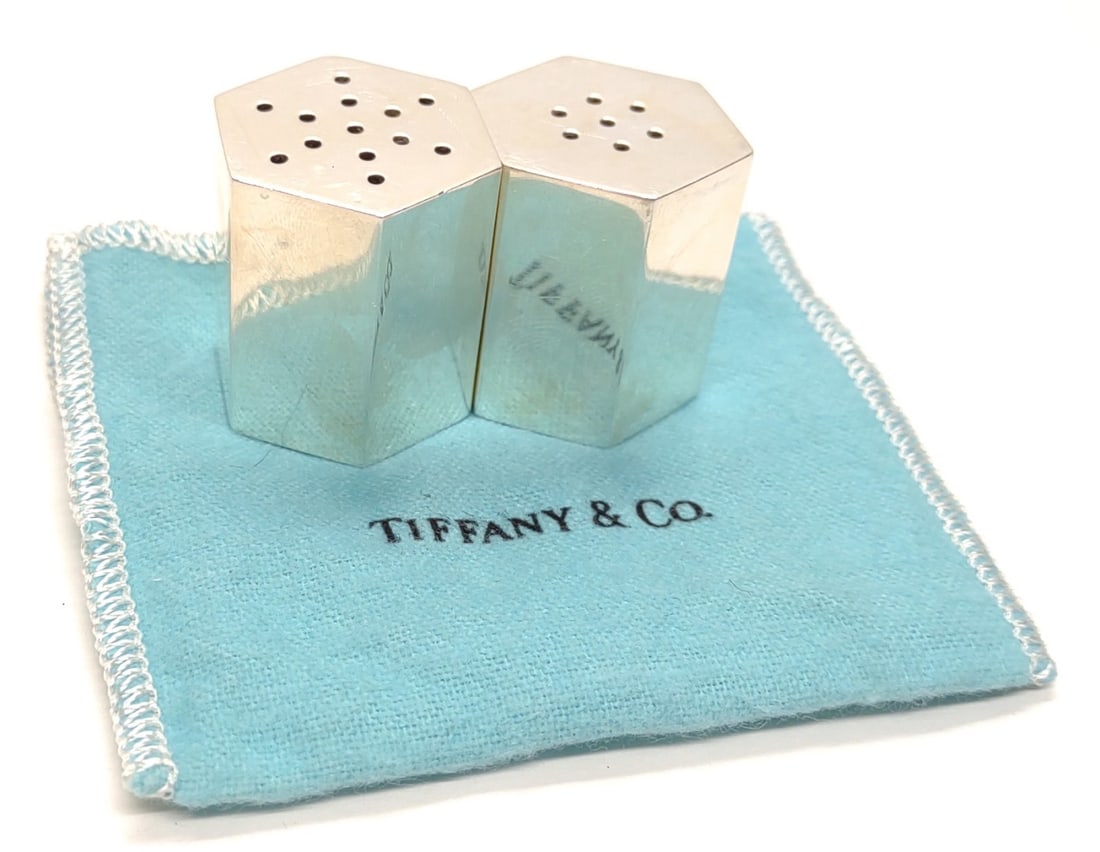 Tiffany & Co Sterling Silver Hexagonal Shaker Set: A pair of sterling silver Tiffany & Co salt and pepper shakers with tiffany & co pouch. Hexagonal shaped. 30mm tall. Both shakers include screw caps on underside. Both are marked with tiffany & co hal