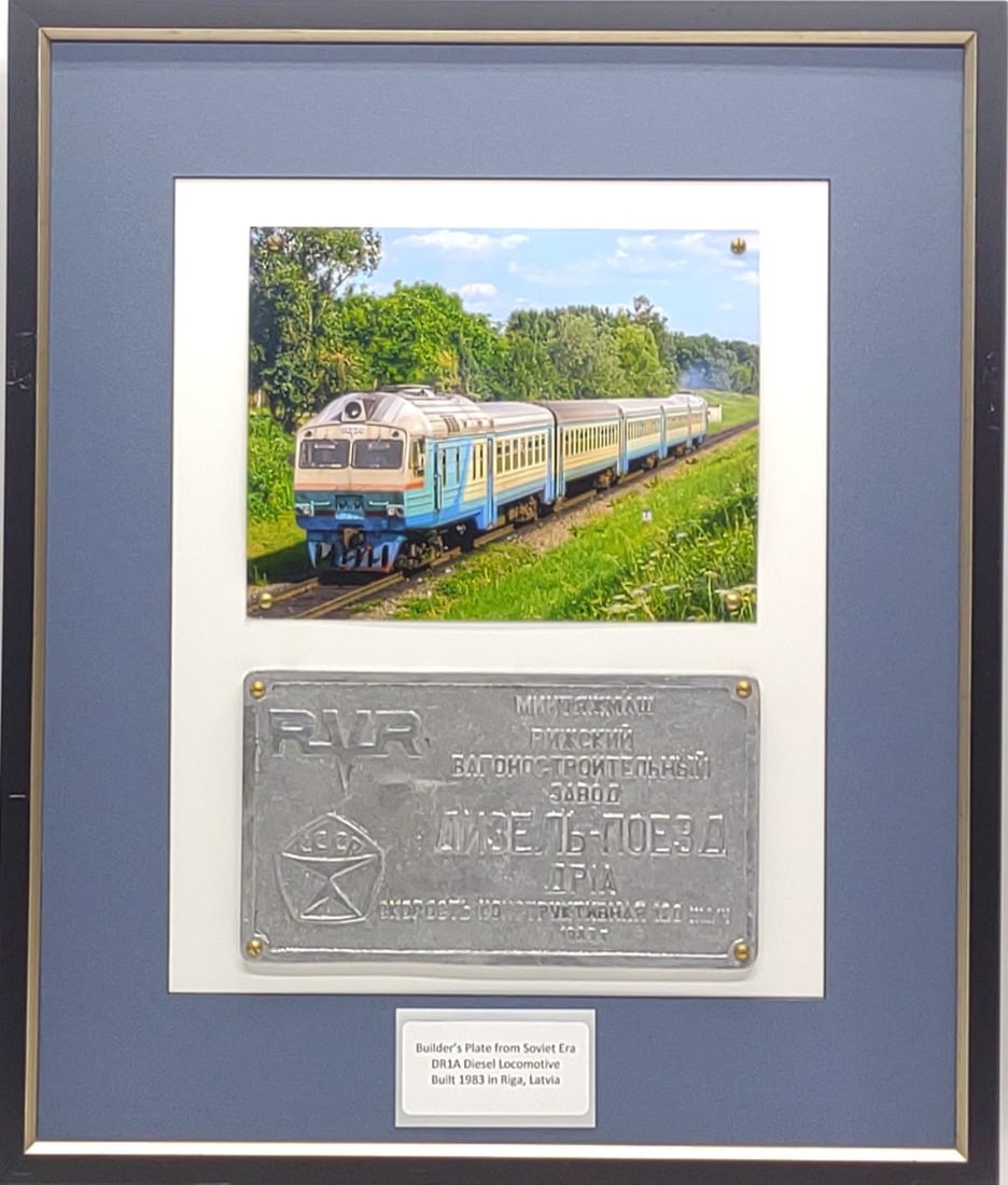 1983 USSR DR1A Diesel Locomotive Builder's Plate: Vintage 1983 Soviet Russian USSR CCCP railroad DR1A diesel locomotive builder's plate. Plate has been framed with picture of original train. Plate measures approximately 11" x 6.25". Frame measures ap