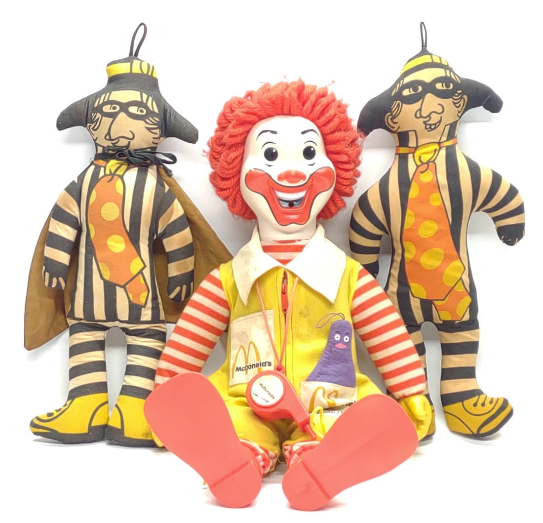 (3) Vintage McDonalds Plush Doll Toys: 3 Vintage McDonalds 1970s soft plush doll toys. Includes 1978 Hasbro Ronald McDonald with grimace and whistle, Hamburglar with cape, and Hamburglar without cape. Largest toy measures approx. 23 x 8 x