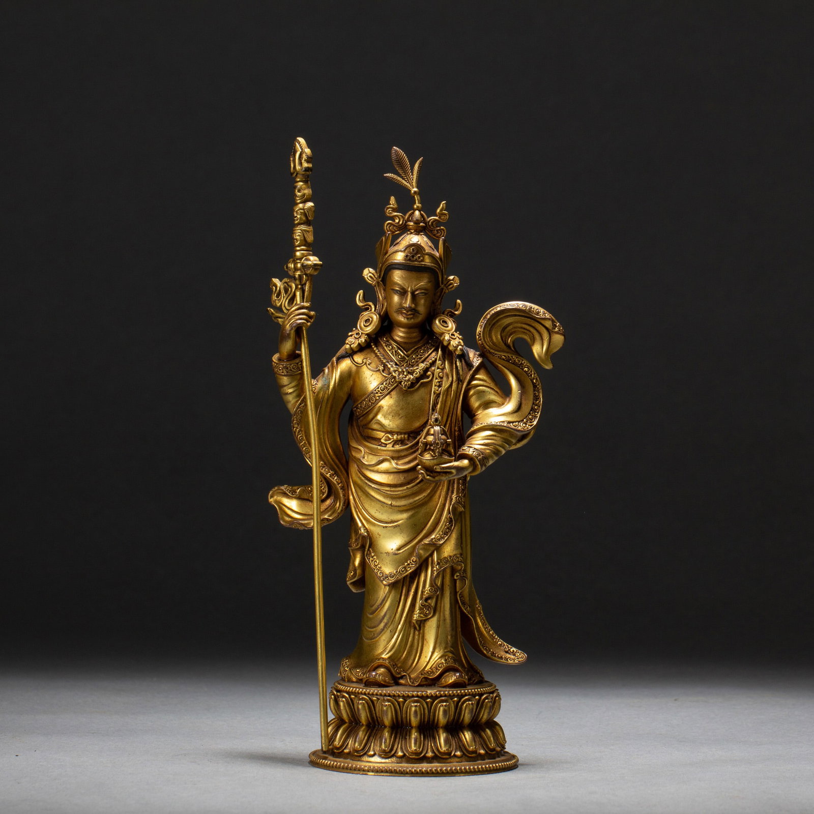 A BRONZE-GILT PADMASAMBHAVA: A BRONZE-GILT PADMASAMBHAVA Padmasambhava (literally ‘lotus-born’ in Sanskrit), also known as Guru Rinpoche among Tibetans, is believed to be one of the principal masters to bring Buddhism to Tibe
