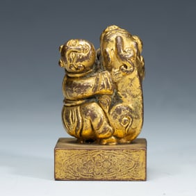 A BRONZE-GILT BOY WITH BEAST SEAL