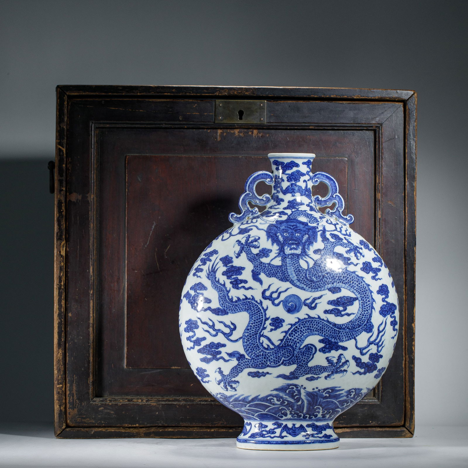 A BLUE AND WHITE DRAGON MOON FLASK BIANHU: A BLUE AND WHITE DRAGON MOON FLASK BIANHU Of circular shape with a spreading rectangular base and a straight neck, flanked by scrolling chilong handles, each side decorated with wrathful dragon, with