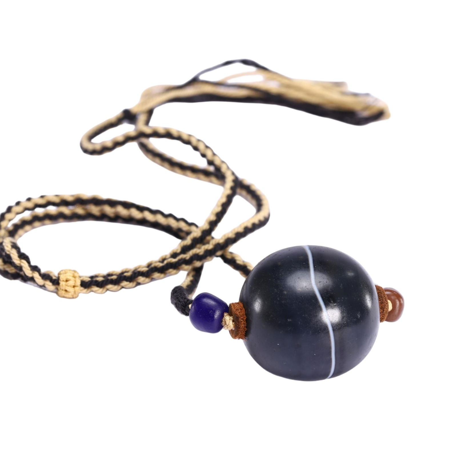 AN AGATE BEAD PENDANT: AN AGATE BEAD PENDANT This Chinese dzi bead pendant necklace features a large, spherical banded agate bead of deep black, bisected by a single, crisp white stripe. Suspended from a braided black and b