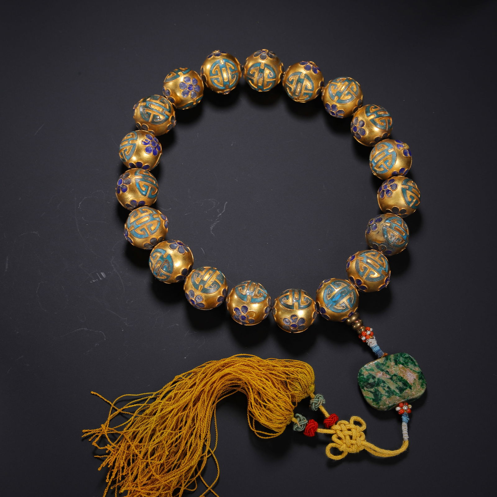 A KING FISHER FEATHER DECORATED BRONZE-GILT PRAYER BEADS SHOUCHUAN: A KING FISHER FEATHER DECORATED BRONZE-GILT PRAYER BEADS SHOUCHUAN This substantial prayer bead strand is composed of eighteen spherical gilt-bronze beads, each intricately decorated with vibrant
