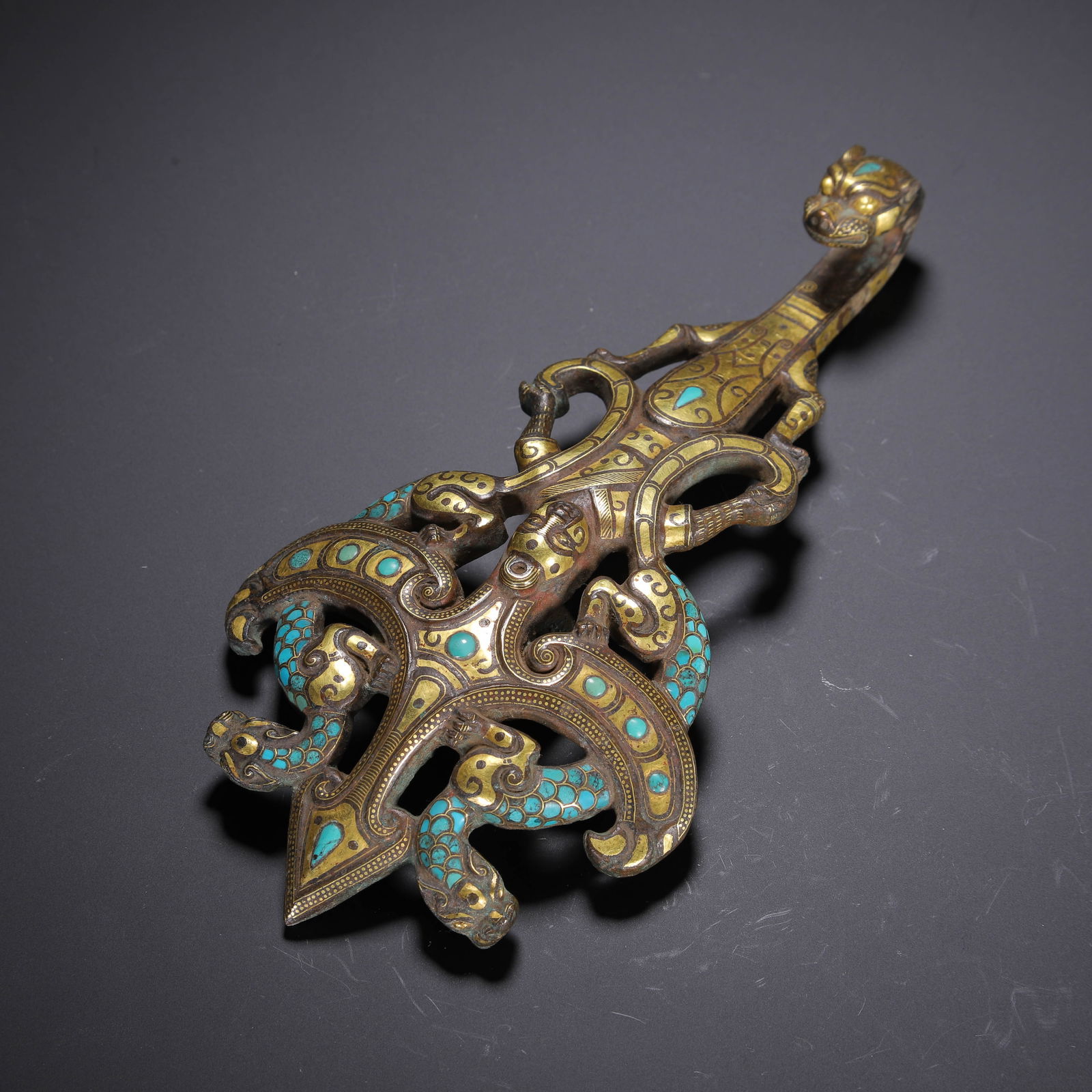 AN IMPORTANT HARDSTONES DECORATED GOLD AND SILVER INLAID BRONZE BELTHOOK: AN IMPORTANT HARDSTONES DECORATED GOLD AND SILVER INLAID BRONZE BELTHOOK This elaborate belt hook is cast in bronze, featuring a sinuous dragon head at the terminal. The body is intricately inlaid wit