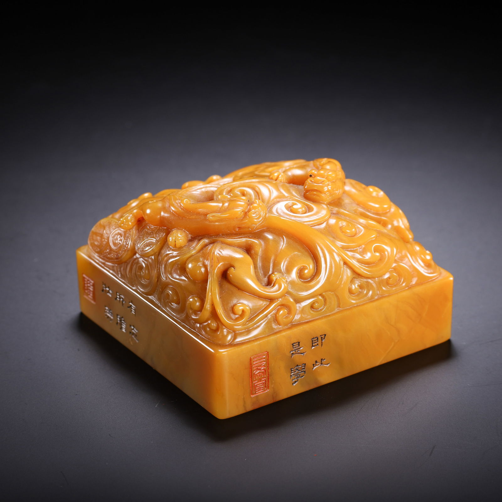 A CARVED TIANHUANG CHILONG GROUP SEAL: A CARVED TIANHUANG CHILONG GROUP SEAL This square seal is carved from a fine block of Tianhuang stone, prized for its rich, honey-yellow hue and smooth, waxy luster. The top is exquisitely decorated