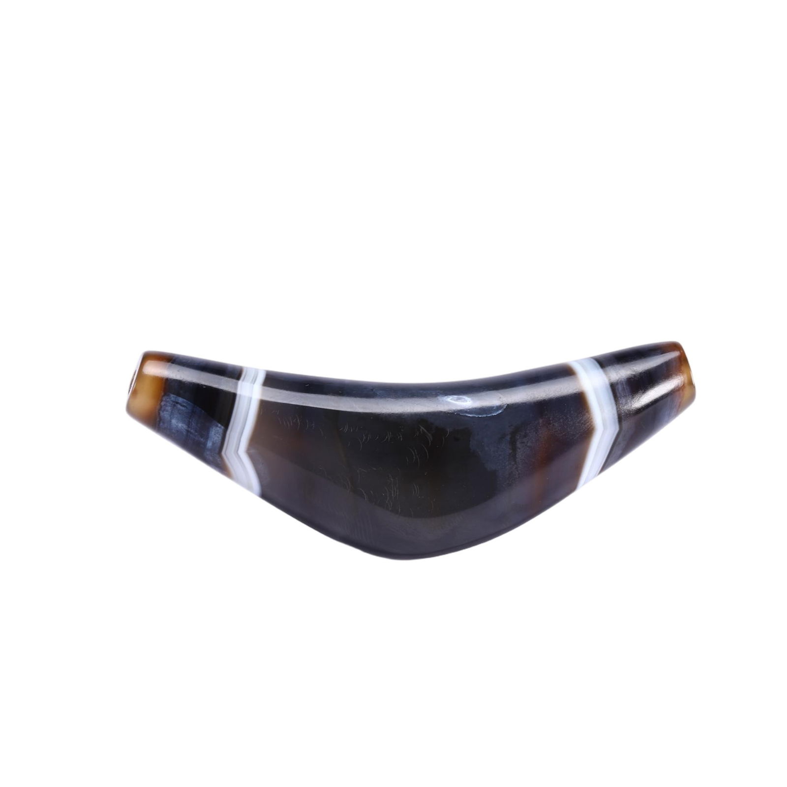 A TIBETAN DZI BEAD: A TIBETAN DZI BEAD This distinctive Chinese agate dzi bead features a unique curved, horn-like form, crafted from a richly banded agate with deep brown, black, and translucent white layers. The smooth