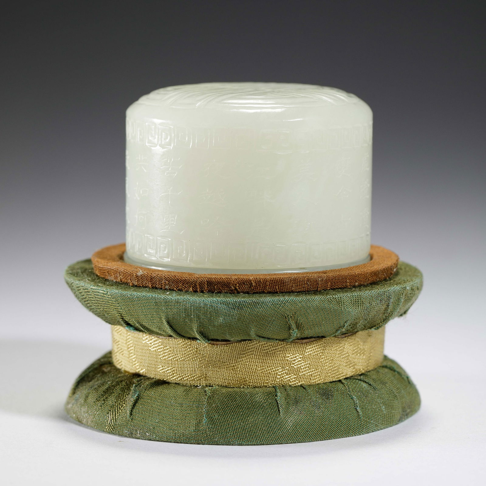 A CARVED WHITE JADE ARCHER RING: A CARVED WHITE JADE ARCHER RING This substantial archer's thumb ring is carved from a single piece of luminous, white Hetian jade. Its cylindrical body is meticulously incised with a continuous poem i