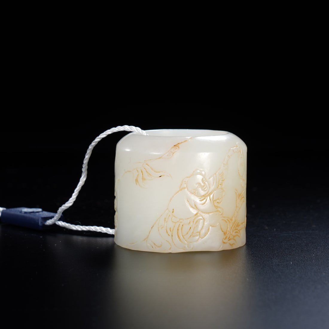 A CARVED WHITE JADE ARCHER RING: A CARVED WHITE JADE ARCHER RING A fine Chinese archer's ring, carved from translucent white jade of a pale, luminous tone. Its exterior is decorated with a delicate, incised scene of a scholar (gaoshi