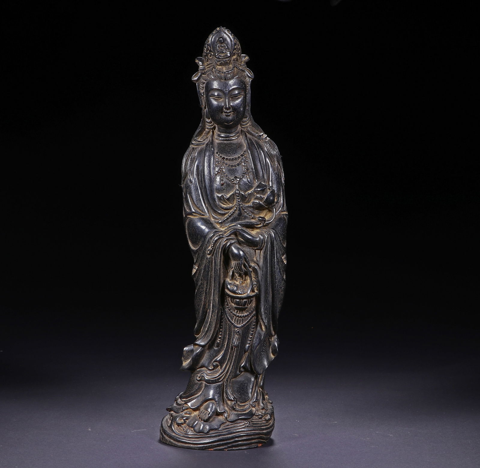 A CARVED ROSEWOOD ZITAN STANDING GUANYIN: A CARVED ROSEWOOD ZITAN STANDING GUANYIN This serene Chinese figure of Guanyin is masterfully carved from a single block of dense zitan wood. The Bodhisattva stands gracefully atop a wave-patterned
