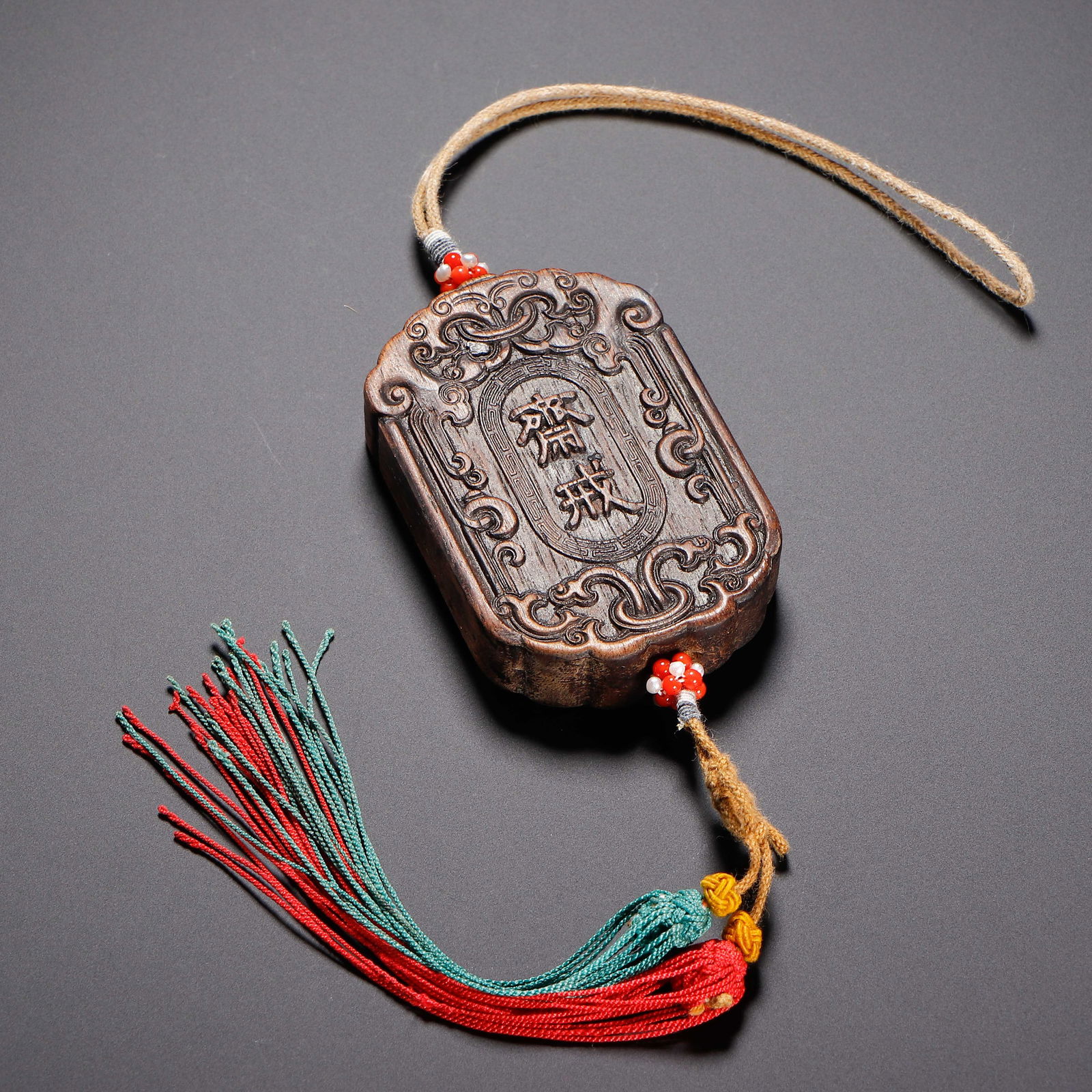 A CARVED ALOESWOOD CHENXIANG ABSTINENCE PLAQUE: A CARVED ALOESWOOD CHENXIANG ABSTINENCE PLAQUE This Chinese abstinence plaque is carved from rich, dark agarwood, with a gently scalloped rectangular form. The surface is intricately carved with scrol