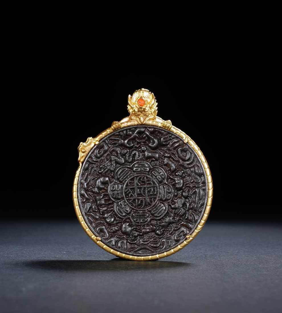 A TIBETAN BRONZE AMULET PENDANT: A TIBETAN BRONZE AMULET PENDANT A powerful Tibetan Buddhist astrological amulet, known as a "Nine Palaces and Eight Trigrams" plaque. The central disc is cast from dark bronze and intricately carved w