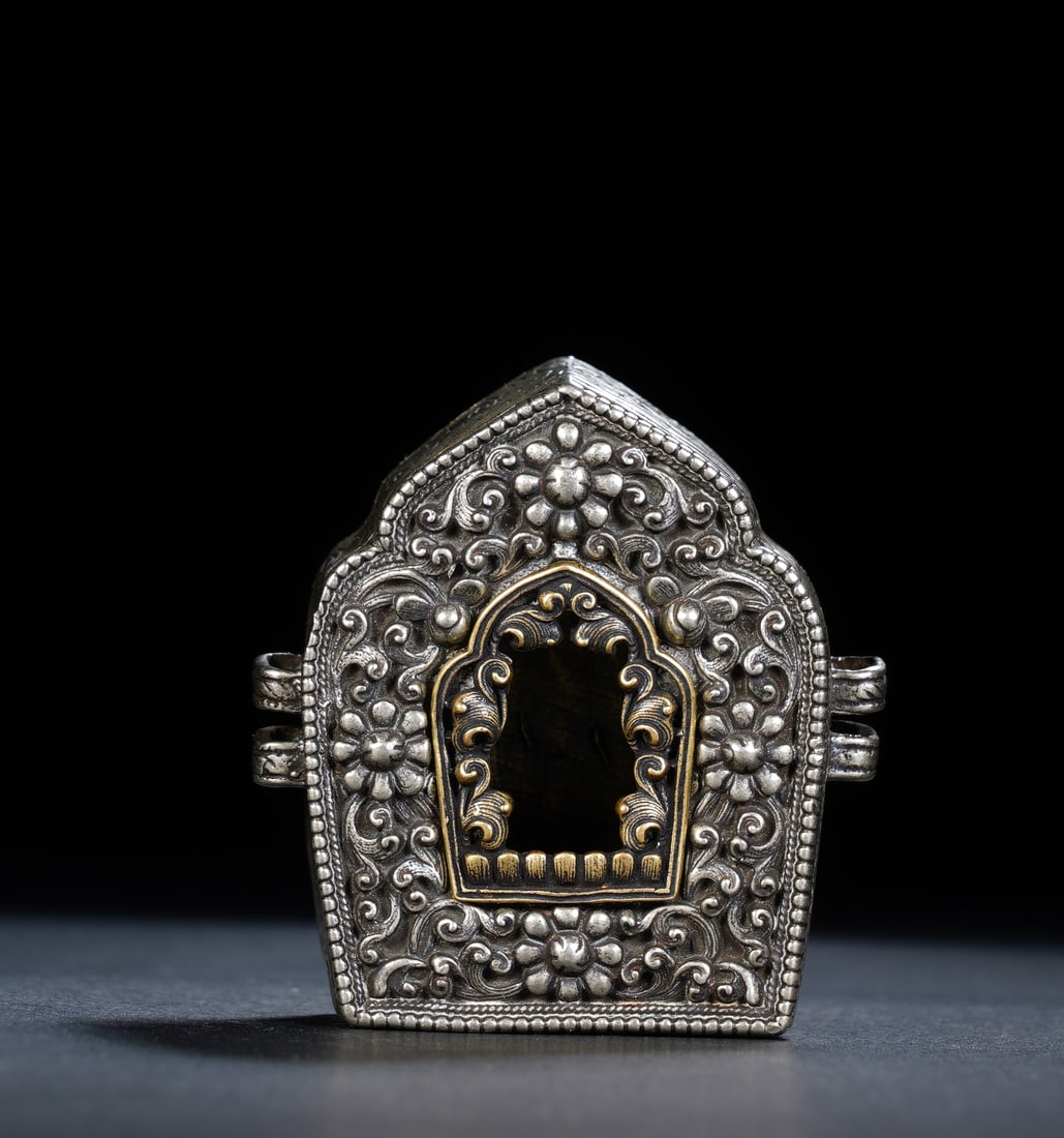 A TIBETAN SILVER PORTABLE SHRINE GAU: A TIBETAN SILVER PORTABLE SHRINE GAU An exquisitely crafted Tibetan Buddhist gau shrine, fashioned entirely from high-grade silver. The exterior is densely decorated with repoussé and chased