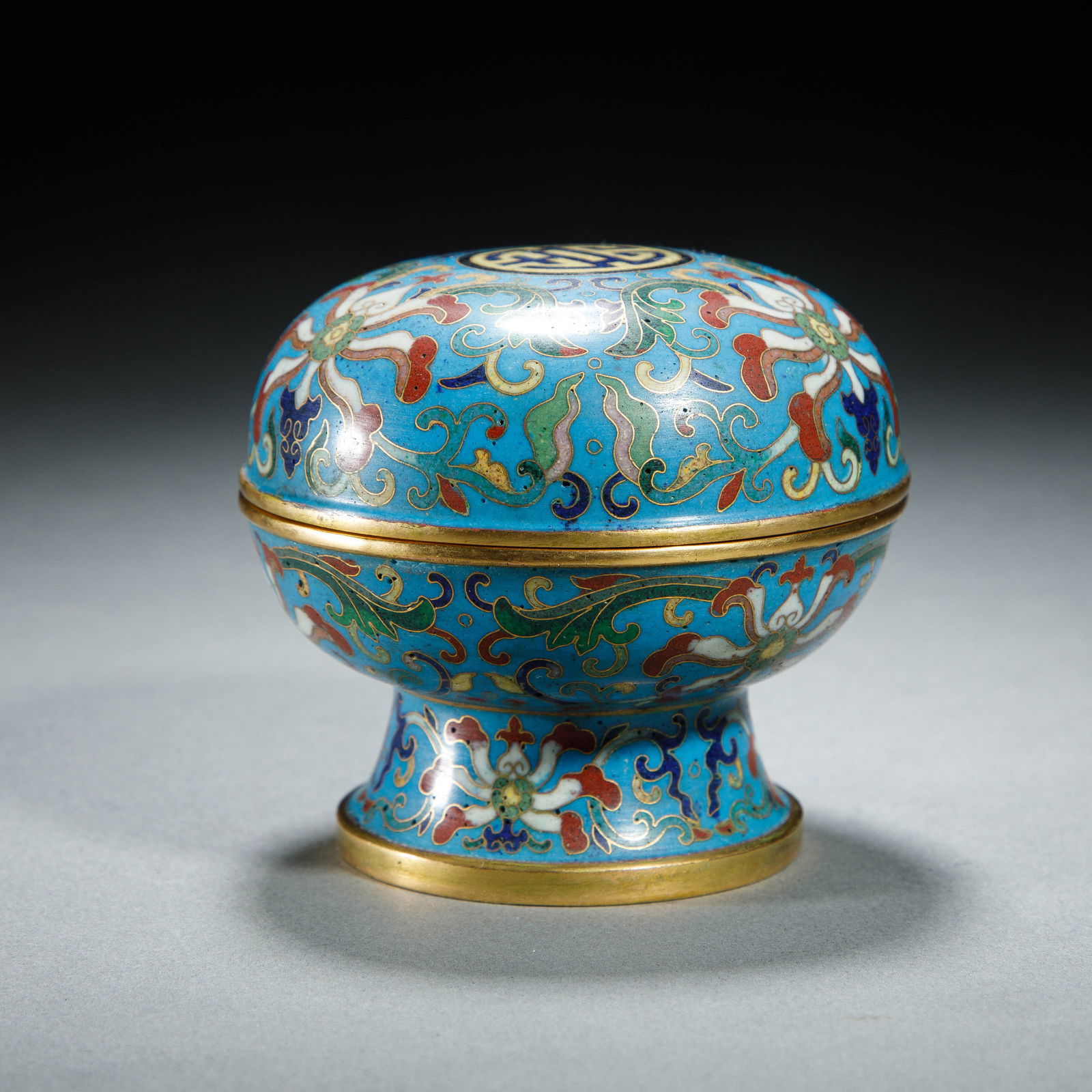 A CLOISONNE ENAMEL COSMETIC BOX WITH COVER: A CLOISONNE ENAMEL COSMETIC BOX WITH COVER An elegant Chinese cloisonné enamel stemmed covered box, the compressed globular body rising from a spreading, flared foot, surmounted by a domed cover.