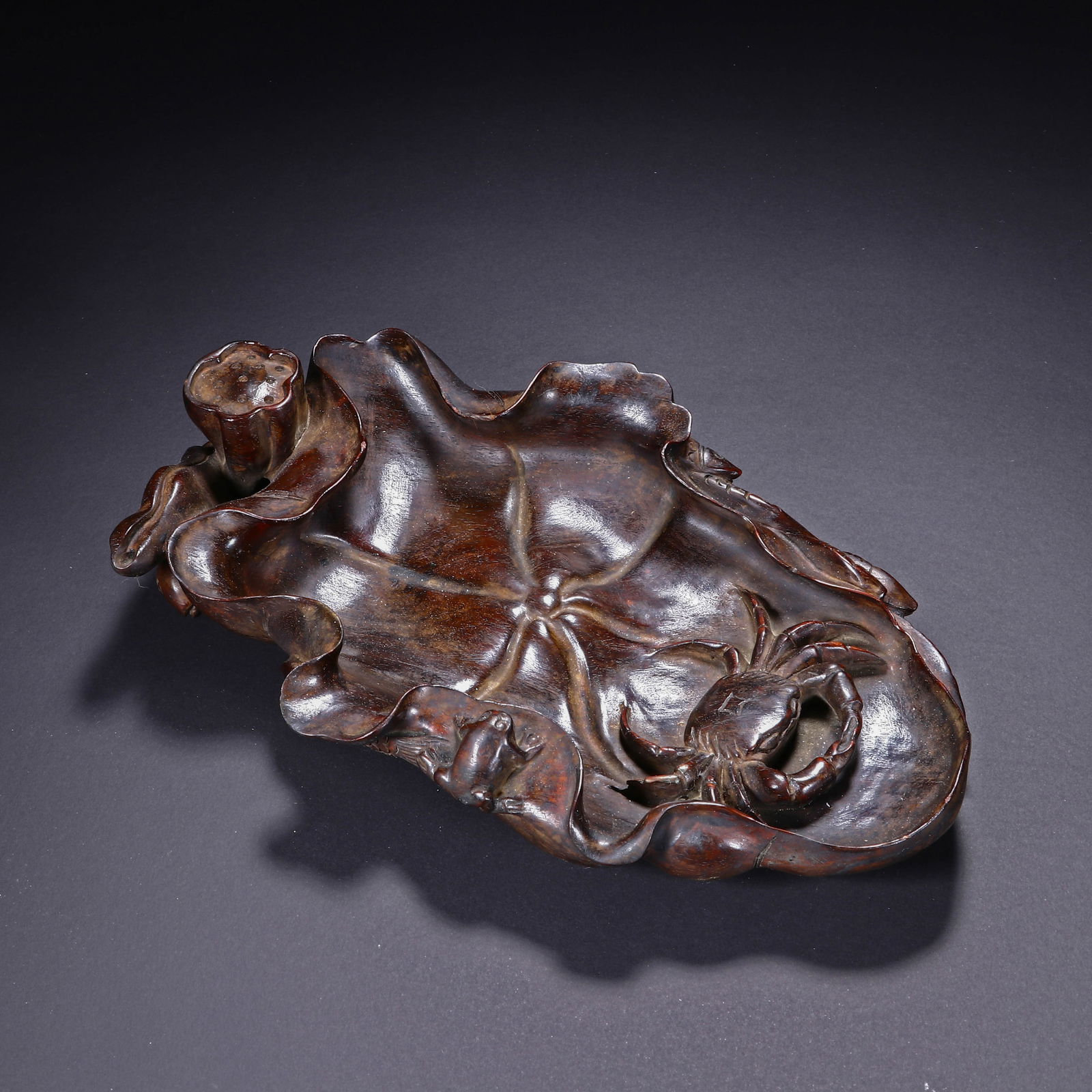 A CARVED HUANGHUALI INKWELL: A CARVED HUANGHUALI INKWELL This exquisite Chinese brush washer is masterfully carved from a single piece of richly hued huanghuali wood, shaped as a naturalistic lotus leaf. The interior is detailed