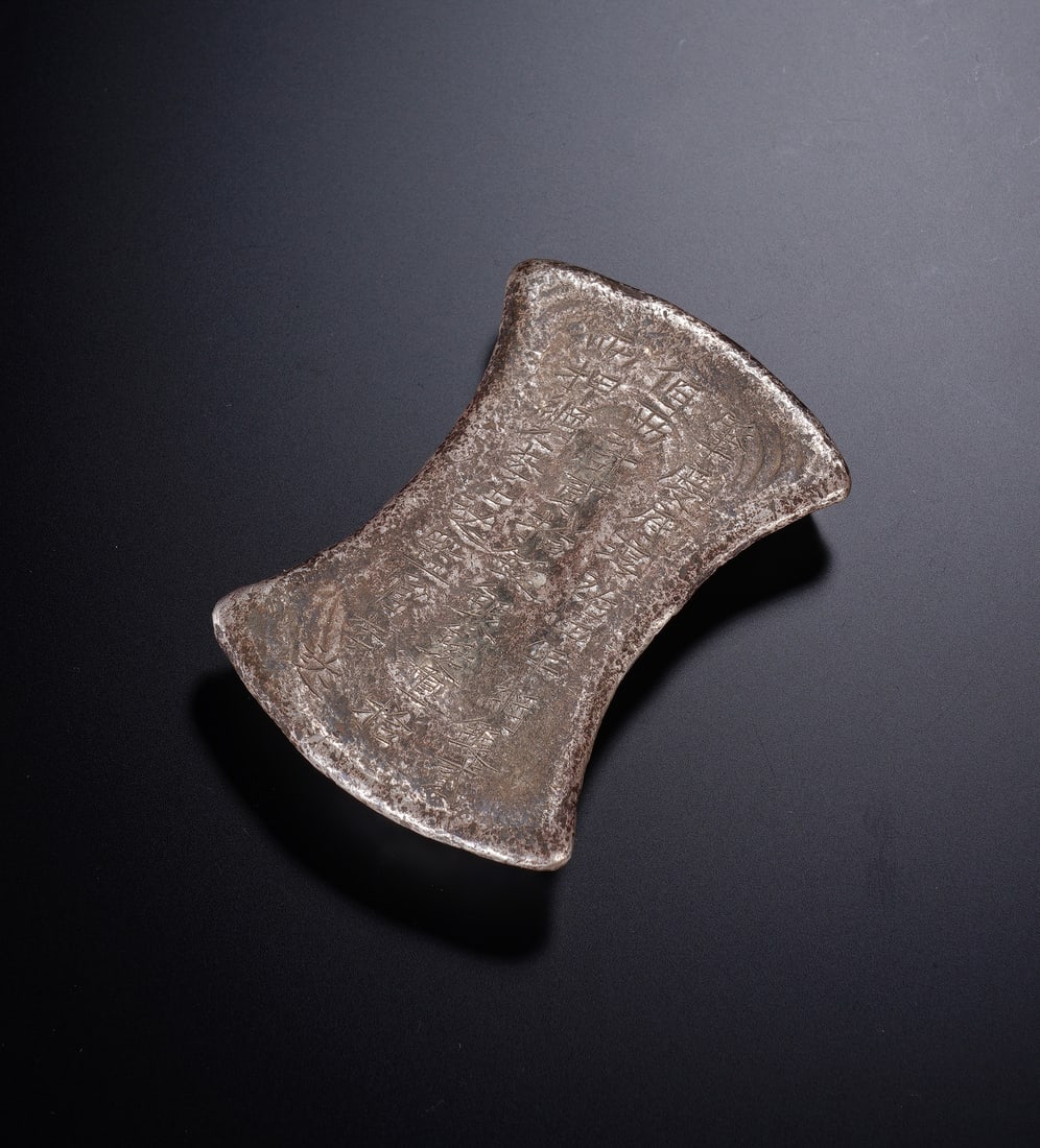 A CHINESE SILVER INGOT: A CHINESE SILVER INGOT An important Chinese silver sycee ingot, cast in the classic boat shape with a textured surface bearing official stamps and inscriptions that attest to its origin and purity. Th