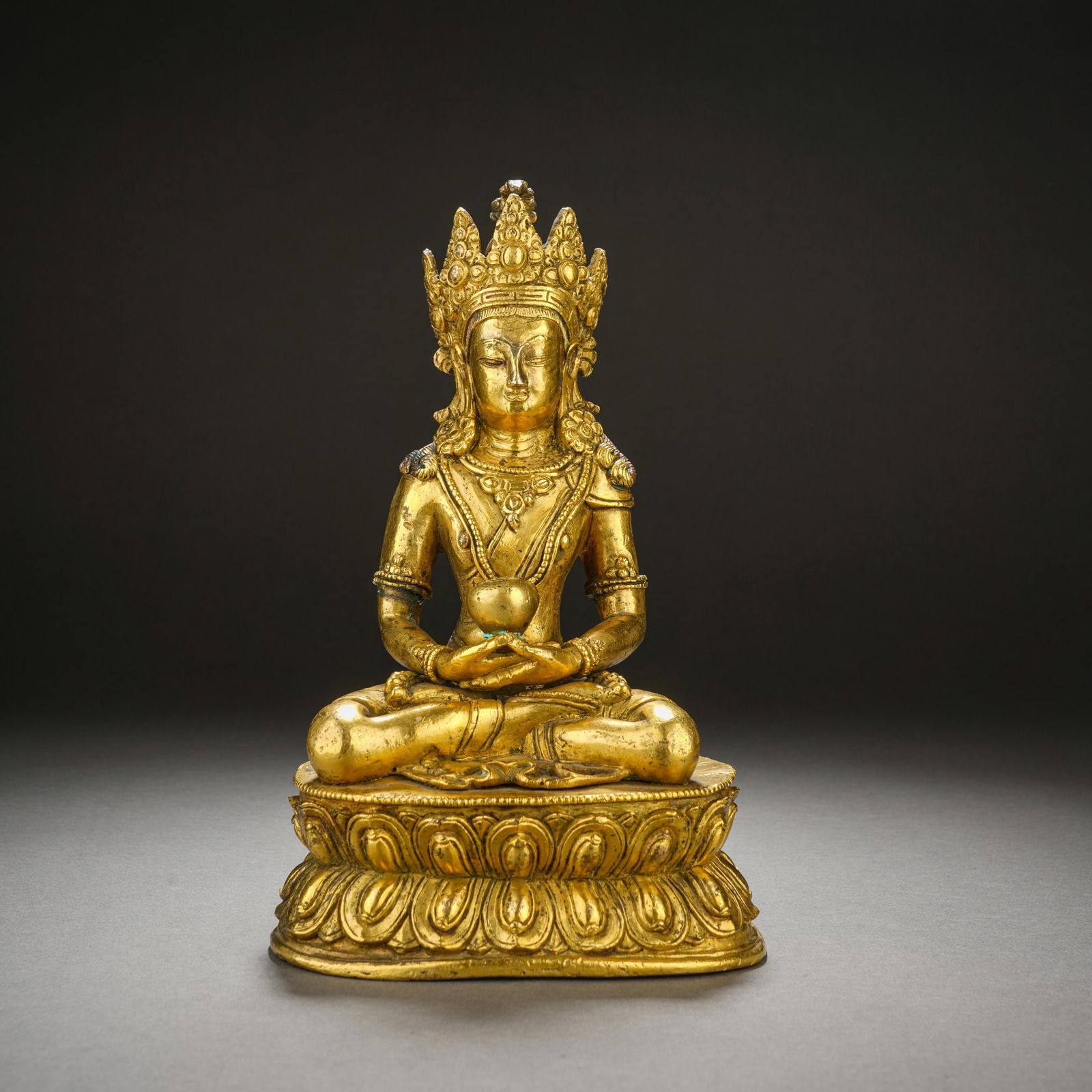 A BRONZE-GILT FIGURE OF AMITAYUS: A BRONZE-GILT FIGURE OF AMITAYUS A fine Chinese gilt-bronze figure of Amitayus, the Buddha of Infinite Life, seated in dhyanasana (meditation pose) upon a double lotus base. The figure wears an ornate