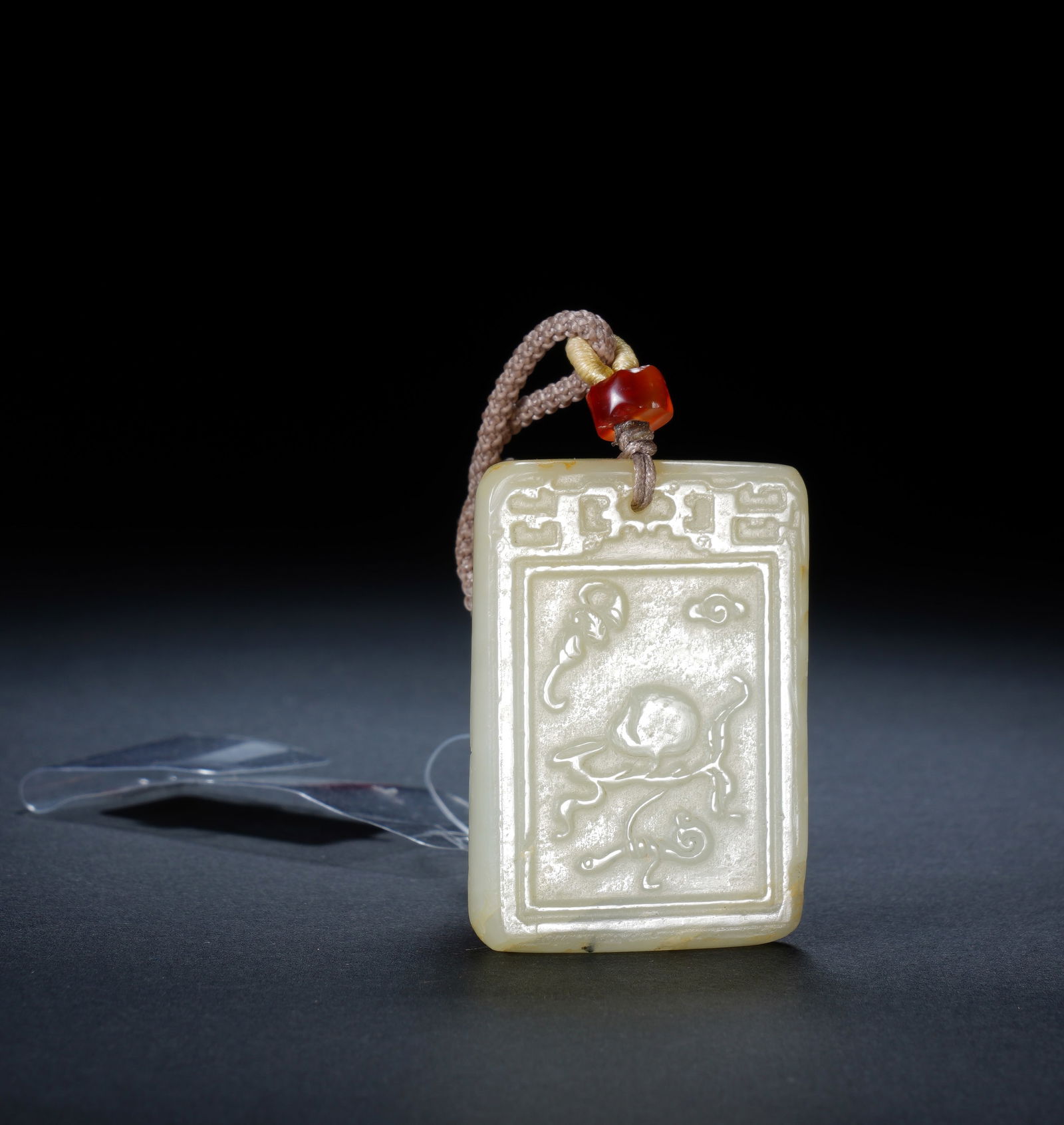 A CARVED WHITE JADE ABSTINENCE PLQUE: A CARVED WHITE JADE ABSTINENCE PLQUE An elegant and finely carved Hetian white jade plaque, rectangular in form with a subtle warm patina. The front is decorated in low relief with a mythical qilin
