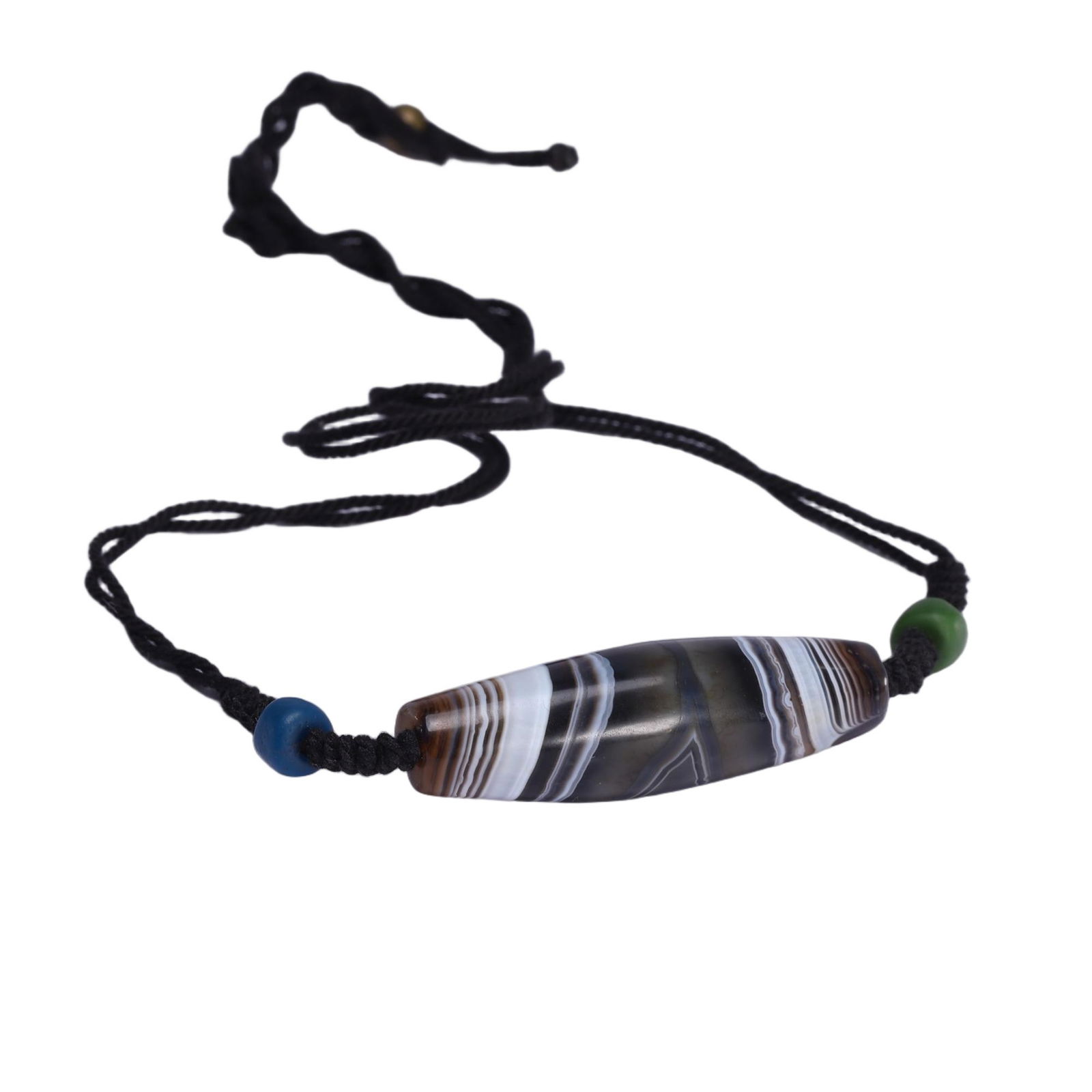 A TIBETAN DZI BEAD PENDANT: A TIBETAN DZI BEAD PENDANT This Chinese agate dzi bead pendant necklace features an elongated bead of banded agate, with concentric layers of deep brown, grey, and milky white. Suspended from a black