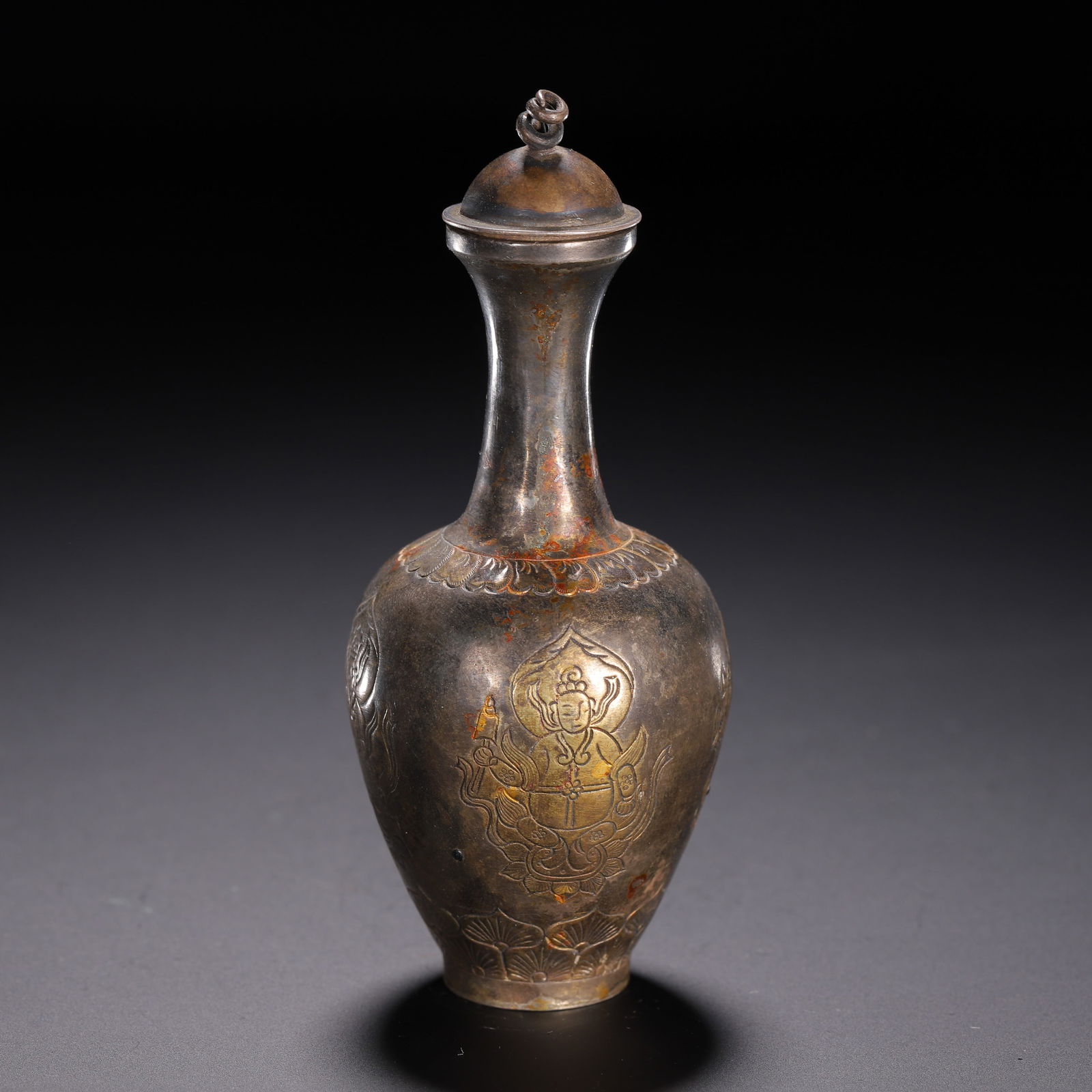 A BRONZE PARTLY GILT VASE WITH COVER: A BRONZE PARTLY GILT VASE WITH COVER This elegant vase is crafted from silver with a rich, aged patina, shaped in a slender baluster form with a domed lid topped by a spiraled finial. The body is