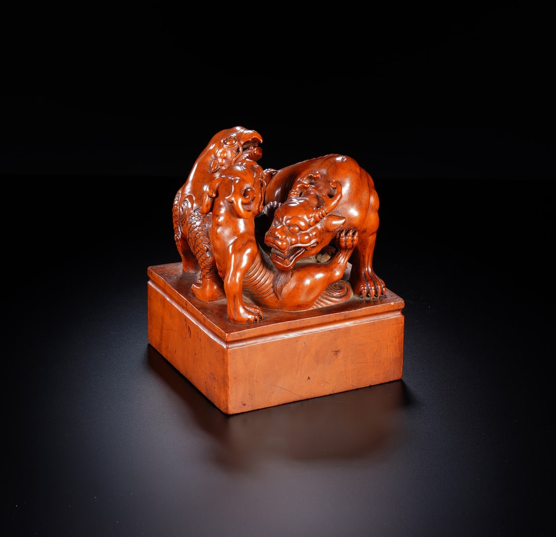 A CARVED BOXWOOD MYTHICAL BEASTS SEAL: A CARVED BOXWOOD MYTHICAL BEASTS SEAL An exceptional Chinese seal carved from a single piece of warm, honey-toned boxwood. The square surmount is crowned by a dynamic group of three intertwined mythic
