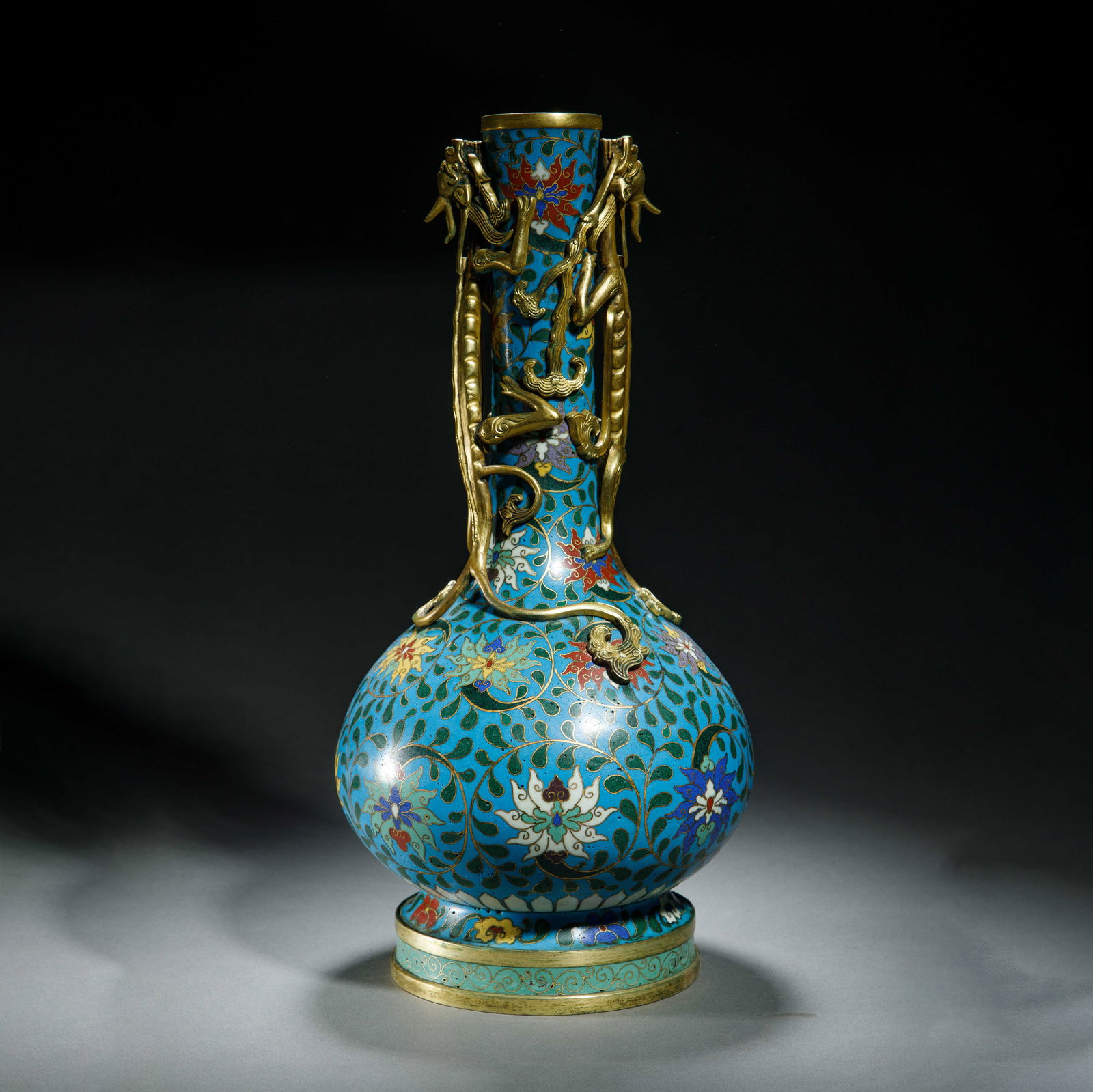 A CLOISONNE ENAMEL DRAGON BOTTLE VASE: A CLOISONNE ENAMEL DRAGON BOTTLE VASE A striking Chinese cloisonné enamel bottle vase, featuring a globular body rising to a tall, slender neck, all set upon a splayed, gilt-banded foot. The vivid s